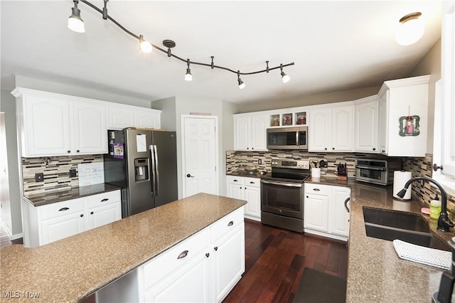 kitchen featuring stainless steel appliances, dark countertops, a sink, and dark wood finished floors