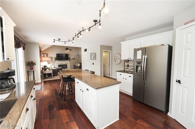 kitchen featuring dark wood-style floors, a center island, a fireplace, open floor plan, and stainless steel fridge