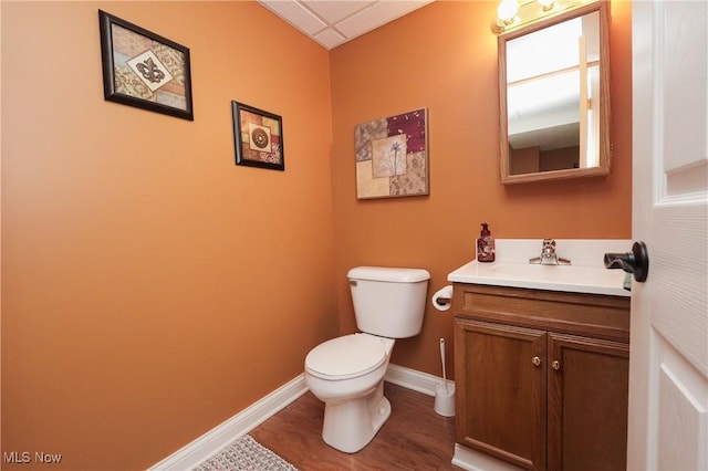 half bath featuring baseboards, vanity, toilet, and wood finished floors