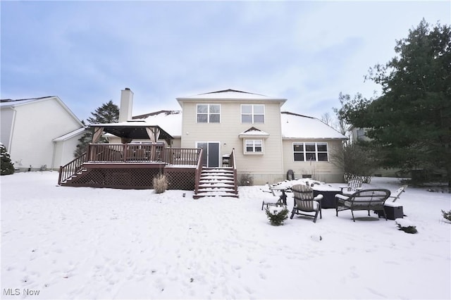 snow covered rear of property with a deck and stairway