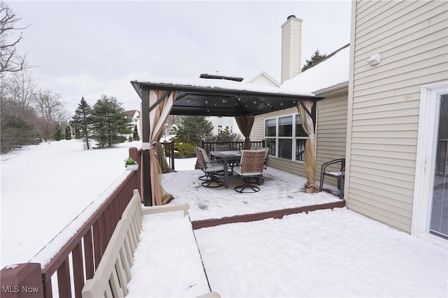 snow covered deck with outdoor dining space and a gazebo