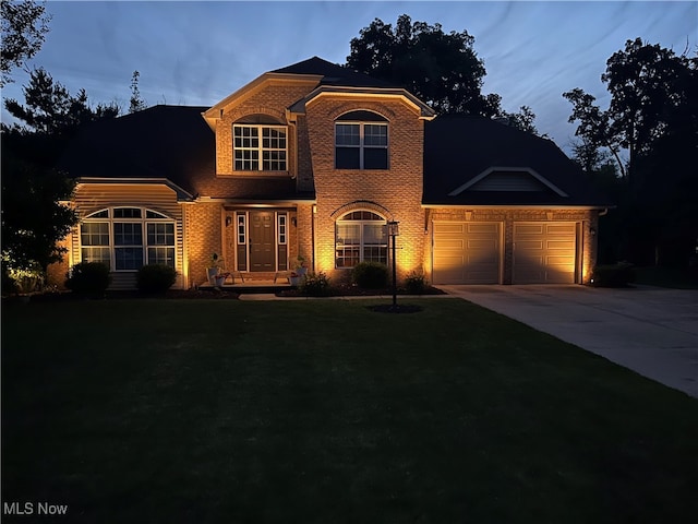 traditional-style house featuring a front yard, concrete driveway, brick siding, and an attached garage