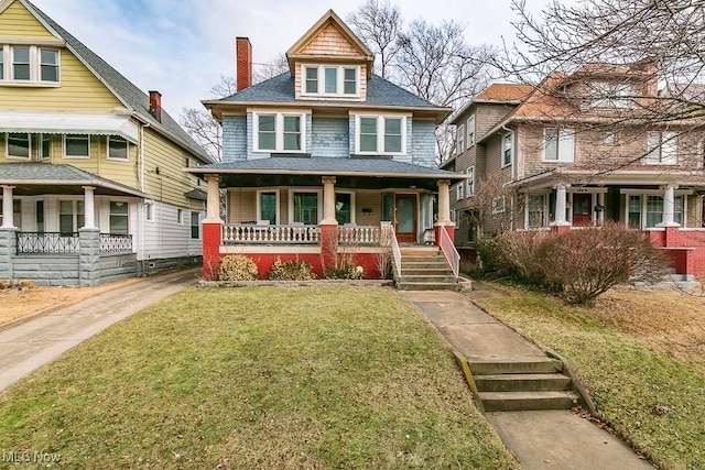 american foursquare style home featuring a porch and a front lawn