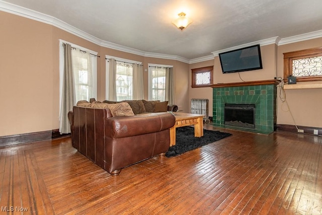 living room with hardwood / wood-style flooring, a fireplace, baseboards, ornamental molding, and radiator