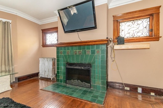 interior details with a fireplace, wood finished floors, baseboards, ornamental molding, and radiator heating unit