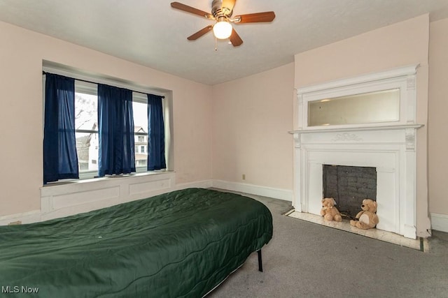 bedroom with a ceiling fan, a fireplace with flush hearth, baseboards, and carpet flooring