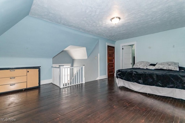 bedroom with lofted ceiling, hardwood / wood-style flooring, baseboards, and a textured ceiling