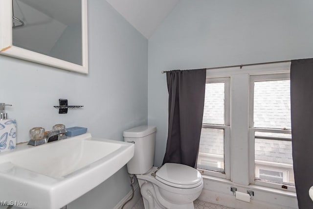 bathroom with lofted ceiling, a sink, and toilet