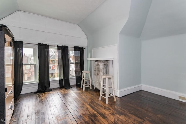 unfurnished room featuring baseboards, vaulted ceiling, and hardwood / wood-style floors