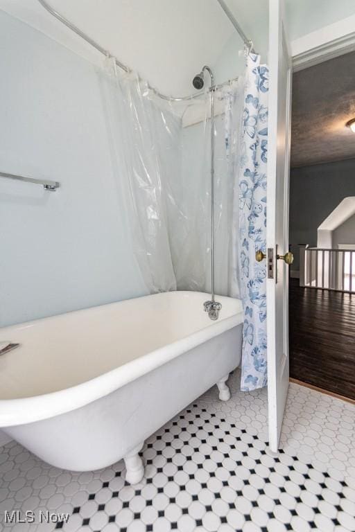 full bath featuring curtained shower and a soaking tub