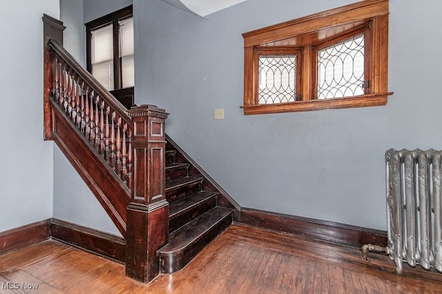 stairs featuring radiator, hardwood / wood-style flooring, and baseboards