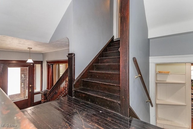 stairway with wood-type flooring and a textured ceiling