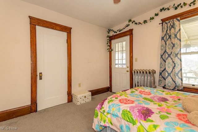 carpeted bedroom featuring multiple windows, radiator heating unit, and baseboards