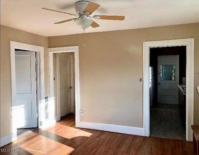 unfurnished bedroom with a closet, ceiling fan, baseboards, and wood finished floors