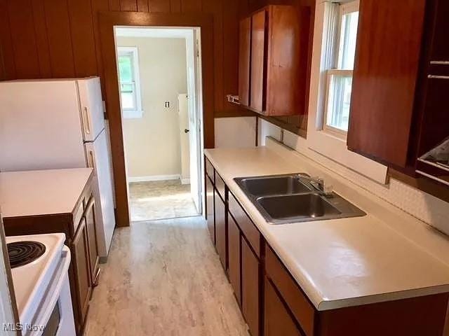 kitchen featuring a wealth of natural light, white appliances, and a sink