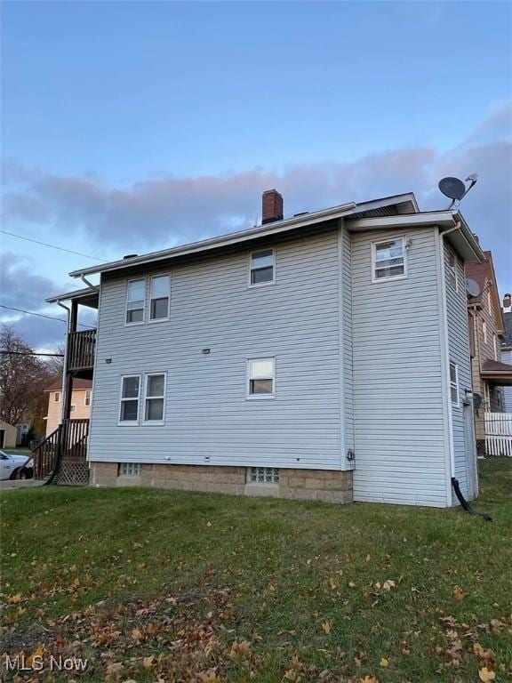 view of side of home with a lawn and a chimney