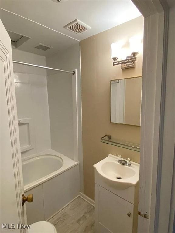 bathroom with visible vents, shower / bathing tub combination, vanity, and wood finished floors