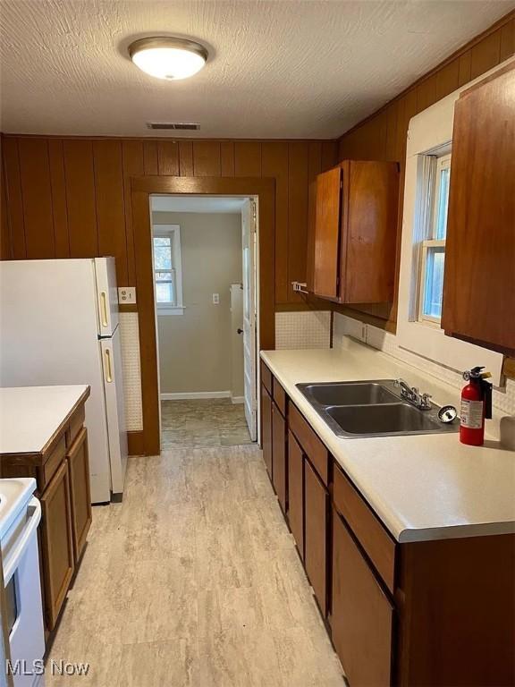 kitchen featuring white appliances, light countertops, and a sink