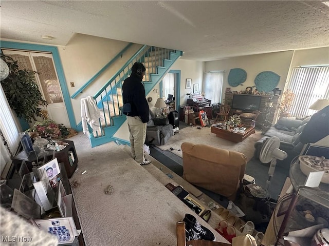 living room with stairway and a textured ceiling