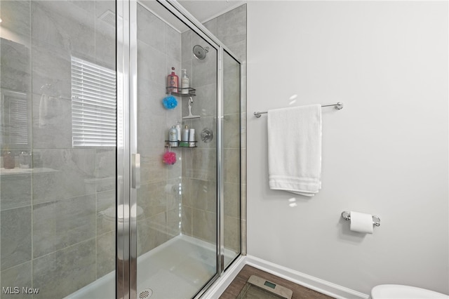 full bath with toilet, a shower stall, baseboards, and wood finished floors