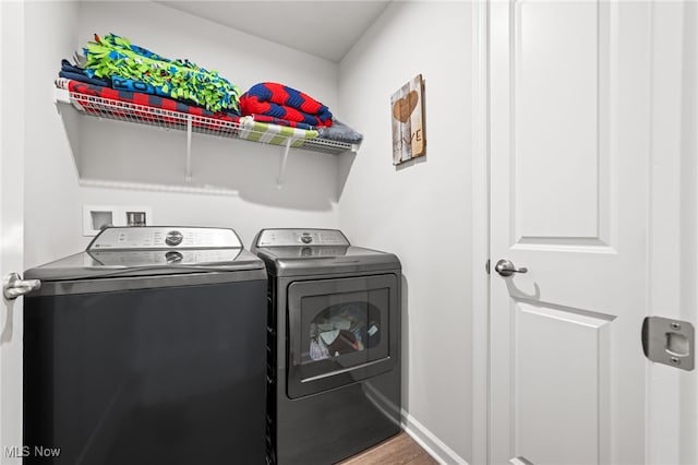 washroom with laundry area, baseboards, washing machine and clothes dryer, and wood finished floors