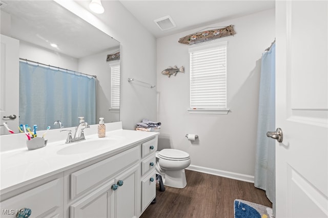 bathroom featuring visible vents, toilet, vanity, wood finished floors, and baseboards