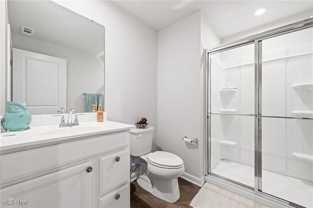 full bathroom with visible vents, toilet, a stall shower, vanity, and wood finished floors