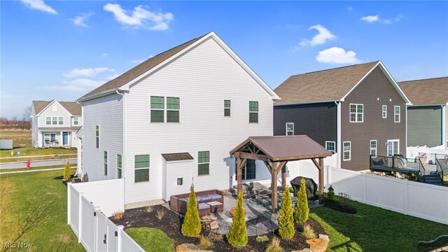 rear view of house with a patio area, a fenced backyard, a lawn, and a gazebo