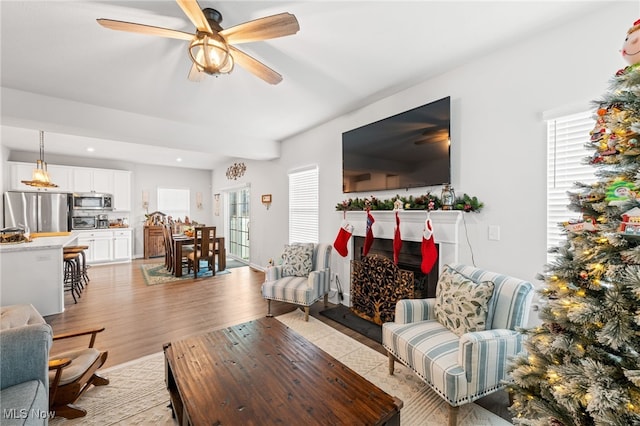 living area with light wood-type flooring, ceiling fan, and recessed lighting