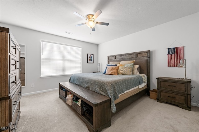 bedroom with ceiling fan, a textured ceiling, light carpet, visible vents, and baseboards