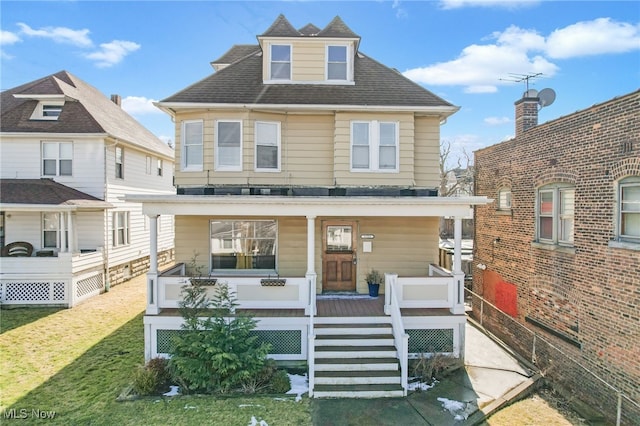 american foursquare style home with a porch, a front yard, and roof with shingles