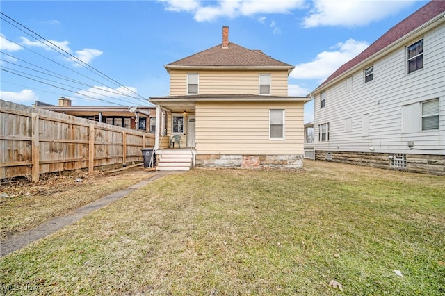 rear view of property with a chimney, fence, and a lawn