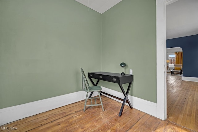 home office featuring arched walkways, baseboards, lofted ceiling, and hardwood / wood-style floors