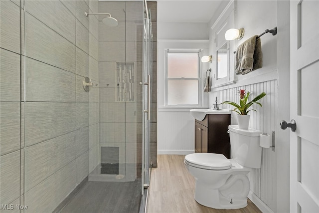 full bath featuring baseboards, toilet, wood finished floors, vanity, and a shower stall