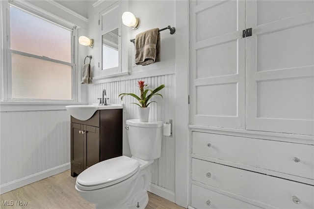 half bathroom featuring wainscoting, vanity, toilet, and wood finished floors