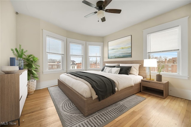 bedroom featuring a ceiling fan, light wood-style flooring, and baseboards