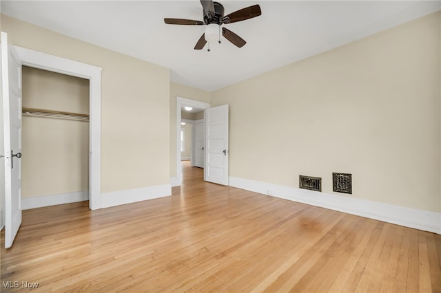 unfurnished bedroom featuring ceiling fan, hardwood / wood-style flooring, visible vents, baseboards, and a closet