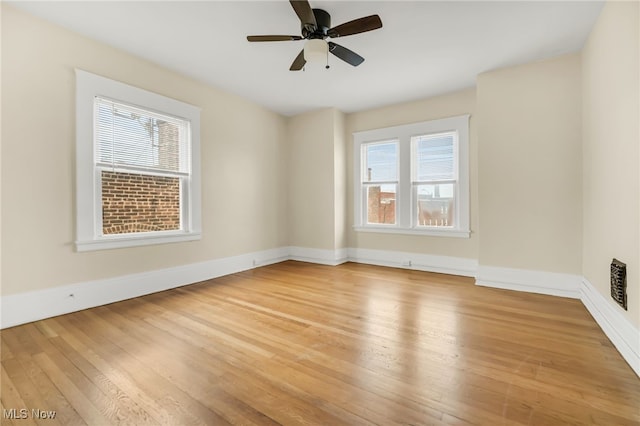 spare room with light wood-style floors, a healthy amount of sunlight, ceiling fan, and baseboards