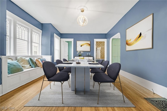 dining space with arched walkways, visible vents, baseboards, and wood finished floors