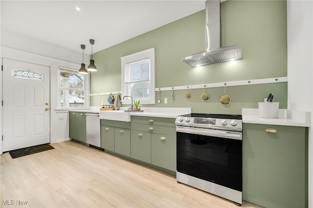 kitchen with a sink, wall chimney range hood, stainless steel appliances, and green cabinetry