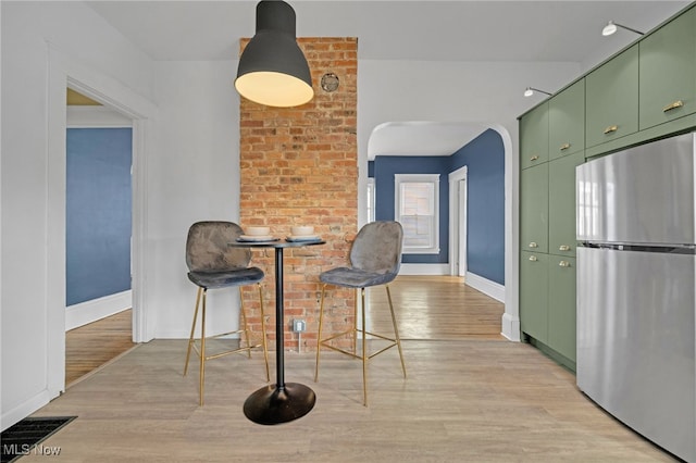 dining room with arched walkways, baseboards, visible vents, and light wood finished floors