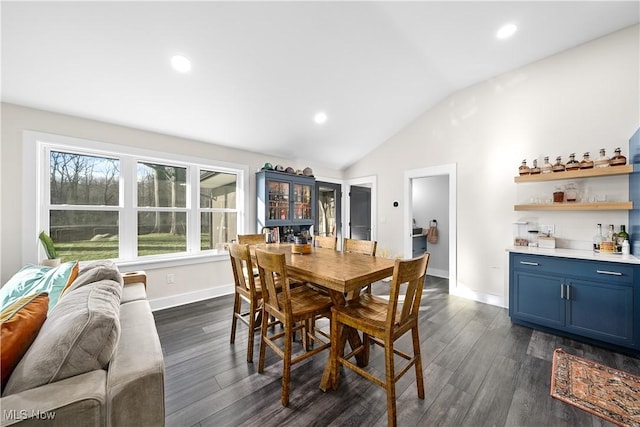 dining space featuring dark wood-style floors, baseboards, vaulted ceiling, and a dry bar