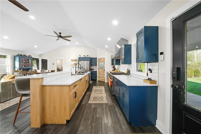 kitchen with open floor plan, vaulted ceiling, a sink, blue cabinets, and high end range