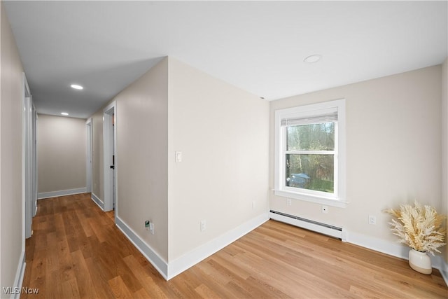 interior space with baseboards, a baseboard heating unit, wood finished floors, and recessed lighting