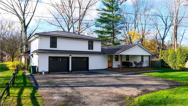 view of front facade featuring an attached garage, fence, aphalt driveway, and a front yard