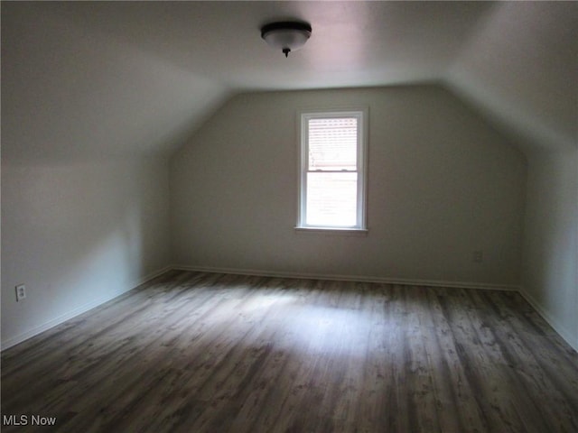 additional living space with lofted ceiling, dark wood finished floors, and baseboards