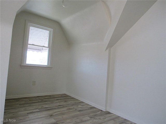 bonus room with baseboards, vaulted ceiling, and wood finished floors