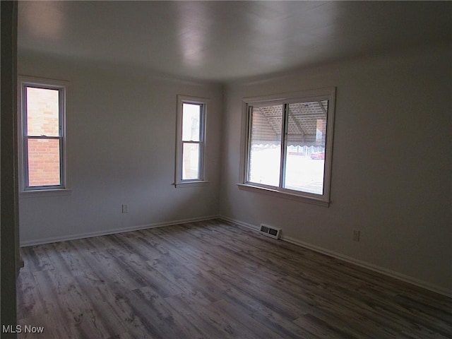 spare room with baseboards, visible vents, and wood finished floors