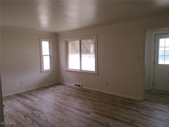 empty room featuring visible vents, dark wood finished floors, and baseboards