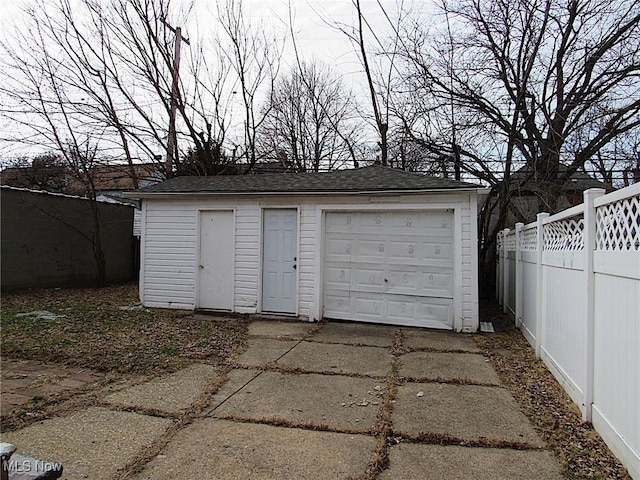 detached garage featuring driveway and fence